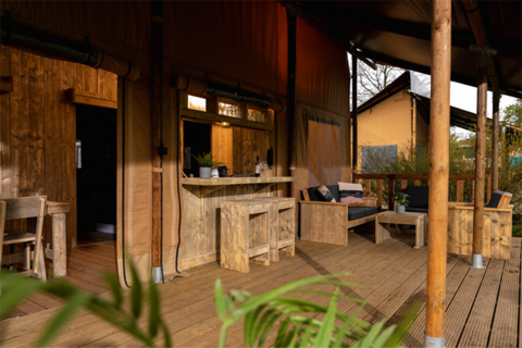 Terrazza in legno con salotto e bar nella tenda safari Glamping Lodge PREMIUM, Le Val de Cesse, Francia.