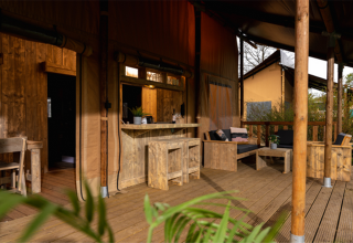 Terrazza in legno con salotto e bar nella tenda safari Glamping Lodge PREMIUM, Le Val de Cesse, Francia.