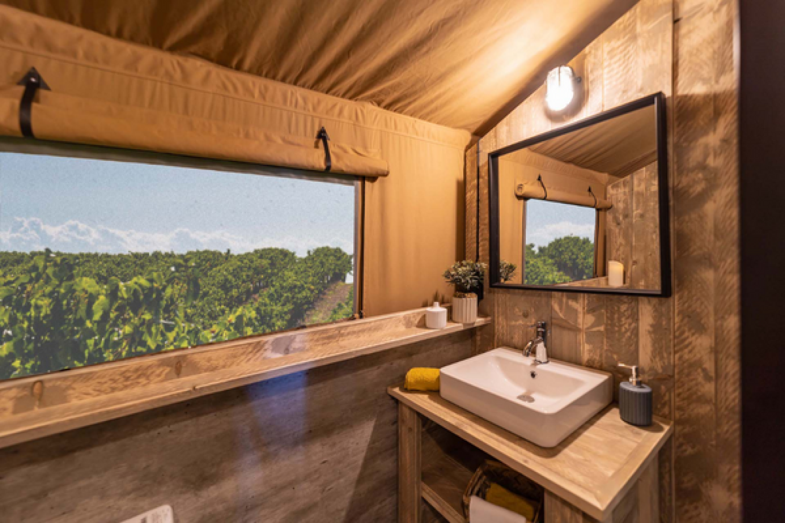 Badkamer met wastafel en houten interieur in een Glamping Lodge PREMIUM safaritent op Camping Le Val de Cesse, Frankrijk.