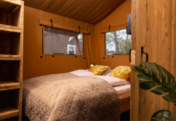 Interno della tenda safari Glamping Lodge PREMIUM con letto comodo al campeggio Le Val de Cesse in Francia.