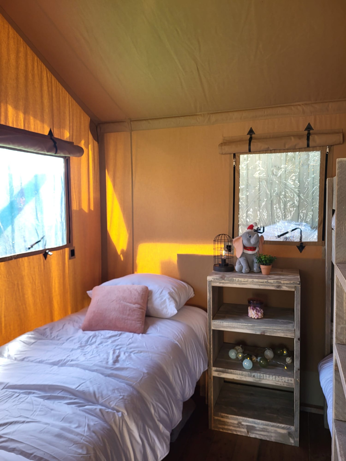 Safari tent interieur met eenpersoonsbed, plank en decoratie in Glamping Lodge PREMIUM, Le Val de Cesse, Frankrijk.