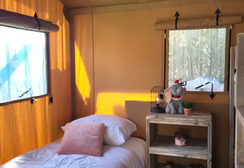 Interno di tenda safari con letto singolo, scaffale e decorazioni al Glamping Lodge PREMIUM, Le Val de Cesse, Francia.