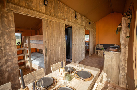 Indretning af Glamping Lodge PREMIUM safari-telt på Camping Le Val de Cesse, Frankrig, med spisebord.