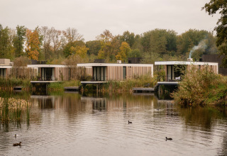 Moderne tiny houses aan het meer in Resort de Parel, Nederland, omgeven door water en natuur.