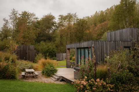 Villa moderne au Resort de Parel aux Pays-Bas, entourée de verdure, arbres et terrasse extérieure en bois.