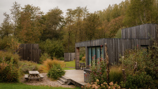 Villa moderne au Resort de Parel aux Pays-Bas, entourée de verdure, arbres et terrasse extérieure en bois.