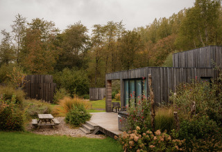 Moderne villa bij Resort de Parel in Nederland, omgeven door groen en bomen, houten terras zichtbaar.