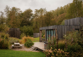 Villa moderne au Resort de Parel aux Pays-Bas, entourée de verdure, arbres et terrasse extérieure en bois.