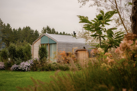 Wrap house met sauna en bad bij Resort de Parel in Nederland, omringd door bloemen en groen.