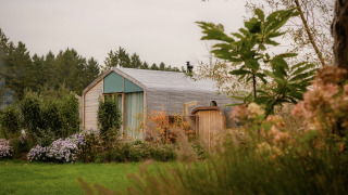 Wrap house met sauna en bad bij Resort de Parel in Nederland, omringd door bloemen en groen.