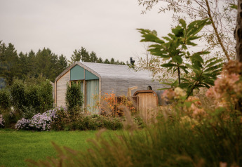 Wrap house met sauna en bad bij Resort de Parel in Nederland, omringd door bloemen en groen.