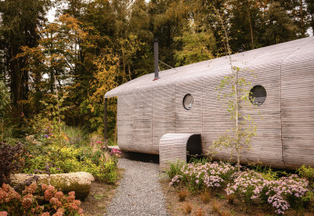 Buitenaanzicht van de Wrap house lodge met sauna en bad bij Resort de Parel, omringd door groen.