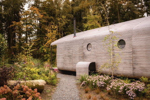 Exterior view of the Wrap house lodge with sauna and bathtub at Resort de Parel, surrounded by greenery.