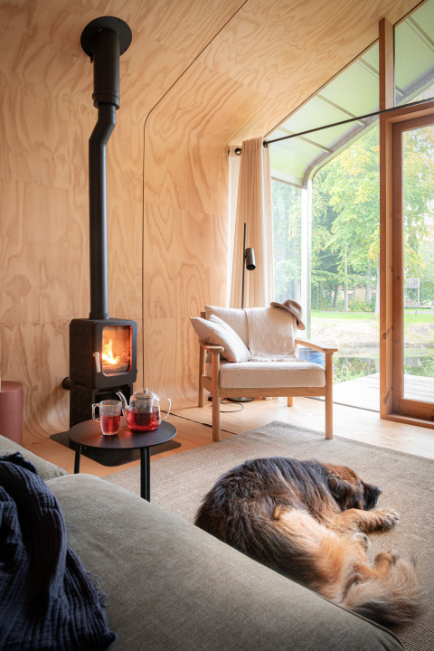 Hyggeligt interiør i Wrap house med pejs, stol, te og sovende hund ved Resort de Parel, Holland.