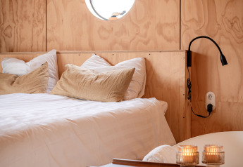 Wrap house lodge met sauna en bad bij Resort de Parel in Nederland, lichte houtlook met rond raam.