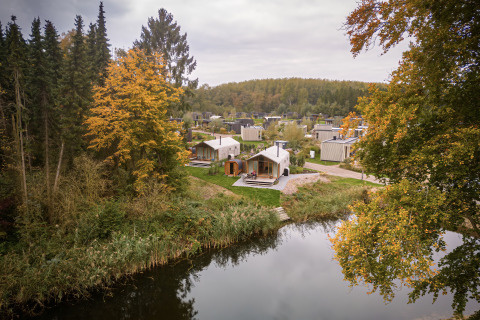Wrap house met sauna en bad bij Resort de Parel in Nederland, omgeven door herfstbomen en een waterrijk landschap.