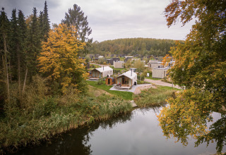 Wrap house lodge with sauna and bathtub at Resort de Parel, Netherlands, surrounded by autumn trees and a lake.