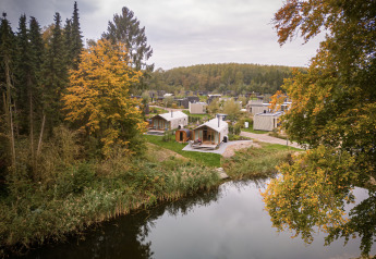 Wrap house avec sauna et baignoire au Resort de Parel aux Pays-Bas, entourée d’arbres d’automne et d’un lac.