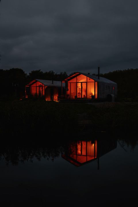 Nachtbeeld van het Wrap House met sauna en bad bij Resort de Parel in Nederland, warm verlicht en weerspiegeld.