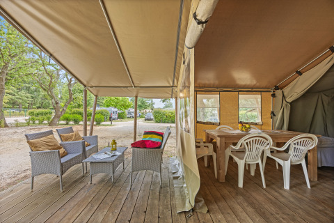 Innen- und Außenbereich des Safarizelts Harmony mit gemütlicher Sitzecke, Esstisch und Naturblick.