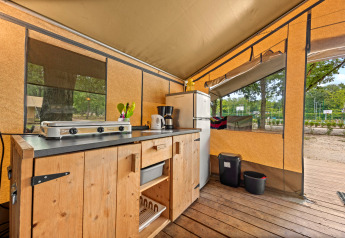 Køkkenområde i en Safaritent Harmony med komfur, køleskab og træbord, perfekt til glamping.