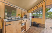 Keukengedeelte in Safaritent Harmony met fornuis, koelkast en houten kast, geschikt voor glamping.