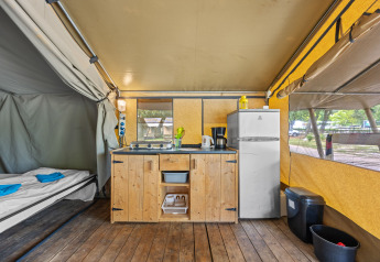 Binnenzicht van Safaritent Harmony met kitchenette, koelkast en bedden binnen een ruime tent.