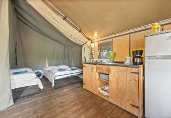 Indretning af Safaritent Harmony med to enkeltsenge, tekøkken, trægulv og køleskab på campingplads.