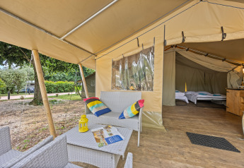 Zona soggiorno accogliente e camera da letto in una tenda safari Safaritent Harmony immersa nella natura.