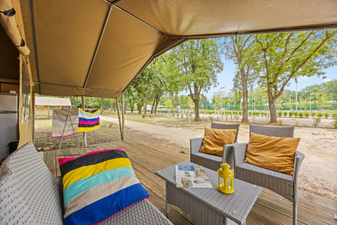 Outdoor seating area of a Safaritent Harmony with chairs, cushions, wooden deck, and a nature view.