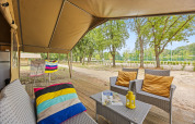 Zona relax esterna di una Safaritent Harmony con poltrone, cuscini e vista sulla natura circostante.
