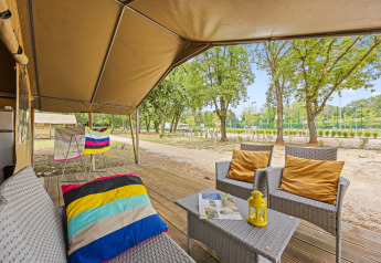 Zona relax esterna di una Safaritent Harmony con poltrone, cuscini e vista sulla natura circostante.