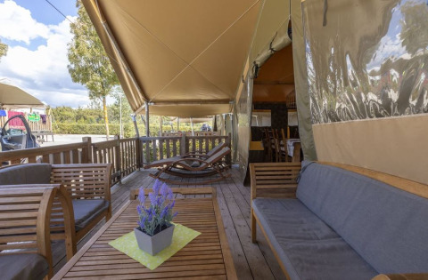 Zona de estar exterior en una Safaritent Sunset en Camping Valkanela, Croacia, con muebles de madera y plantas.