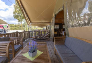 Zona de estar exterior en una Safaritent Sunset en Camping Valkanela, Croacia, con muebles de madera y plantas.