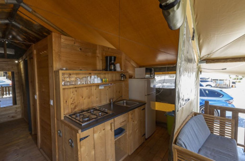 Interno della Safaritent Sunset con cucina, divano e frigorifero al Camping Polari, Croazia, vista esterna.