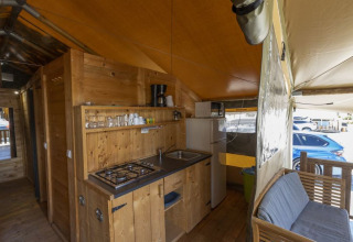 Interior of Safaritent Sunset showing kitchen, sofa and fridge at Camping Polari, Croatia, with outside view.