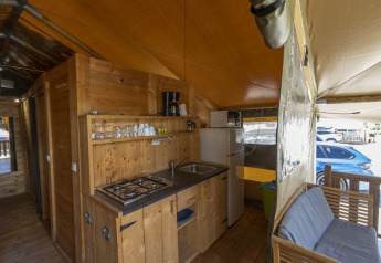 Interno della Safaritent Sunset con cucina, divano e frigorifero al Camping Polari, Croazia, vista esterna.