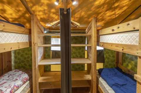 Interior de una tienda safari con literas y estanterías de madera en Camping Valkanela, Croacia.