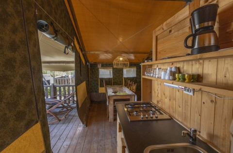 Interior de una tienda safari con cocina, mesa de comedor y madera en Camping Polari, Croacia.