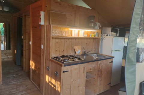 Cocina de madera en una tienda safari en Camping Valkanela, Croacia, con estufa, fregadero y nevera.
