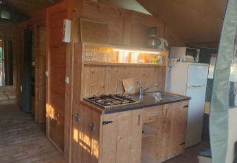 Cocina de madera en una tienda safari en Camping Valkanela, Croacia, con estufa, fregadero y nevera.