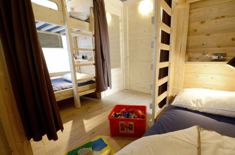 Intérieur d'une tente safari avec lits superposés et boîte à jouets au Camping Polari en Croatie, salle de bain privée.