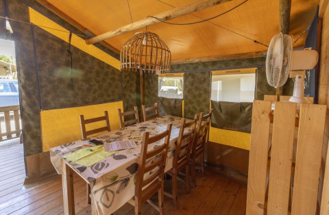 Zona pranzo nella Safaritent Sunset con sedie in legno e ventilatore al Camping Polari, Croazia.