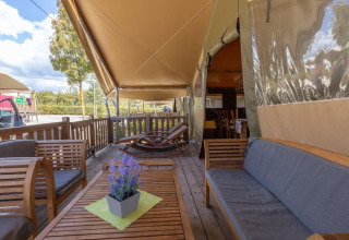 Houten terras met loungezetels aan Safaritent Sunset op Camping Valkanela, Kroatië, vanaf de zijkant gezien.