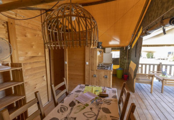 Indretning af Safaritent Sunset med trævægge, spisebord og terrasse på Camping Valkanela i Kroatien.