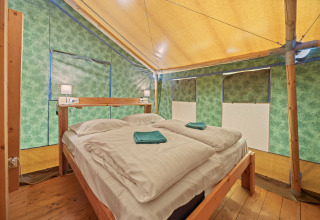 Binnenzicht van Safaritent Sunset op Camping Valkanela in Kroatië met tweepersoonsbed en houten vloer.