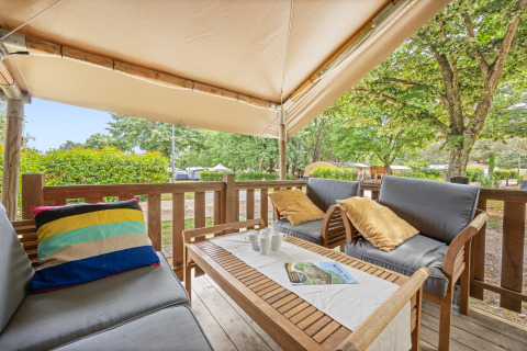 Espace détente sur la terrasse de la Safaritent Relax avec coussins confortables et vue sur la nature.