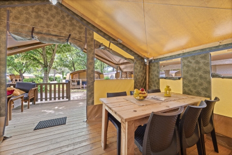 Vista interior de la Safaritent Relax con mesa de comedor, sillas, frutero y acceso a la terraza exterior.