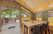 Vue intérieure de la Safaritent Relax avec table à manger, chaises, corbeille de fruits et accès à la terrasse.