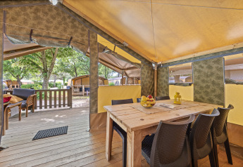 Innenansicht des Safaritent Relax mit Holztisch, Stühlen, Obstschale und Zugang zur Holzterrasse.